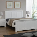 Heartlands white wooden bed with panelled headboard and footboard in a  UK bedroom with drawers and lamps